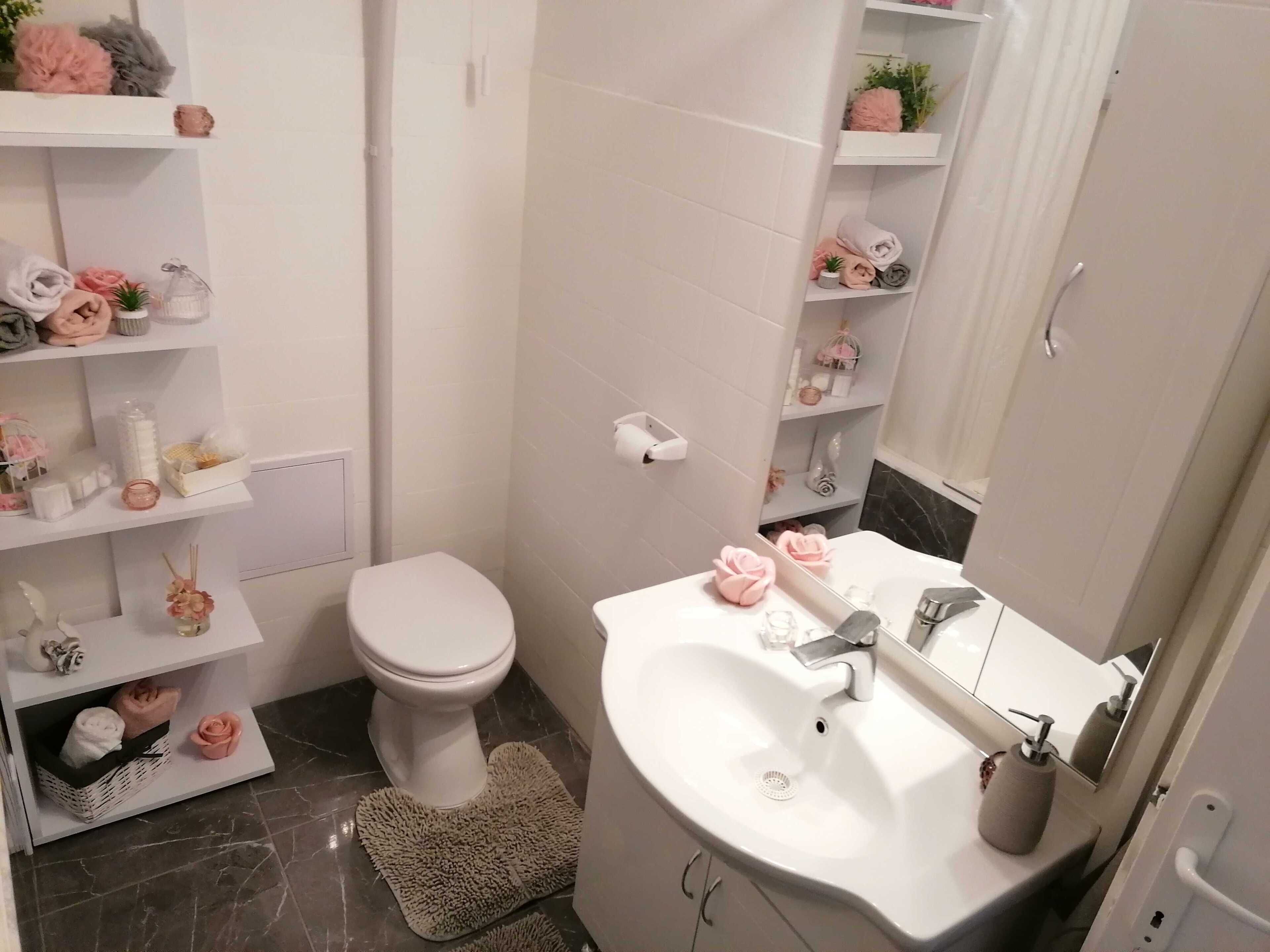 Ein modernes Badezimmer mit Toilette, Waschbecken und Ablagen für Toilettenartikel.