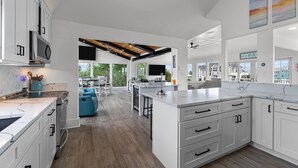 A modern kitchen with white cabinetry, a large island, and a view to the outdoors.