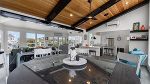 A spacious living area with a large glass table, modern furniture, and a view of the outside.