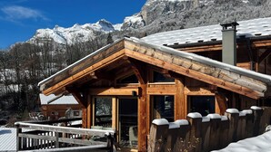 A wooden cabin with a sloped roof, surrounded by snow, and a mountain backdrop. - Chalet Mélèze Vallée de Chamonix (Servoz)