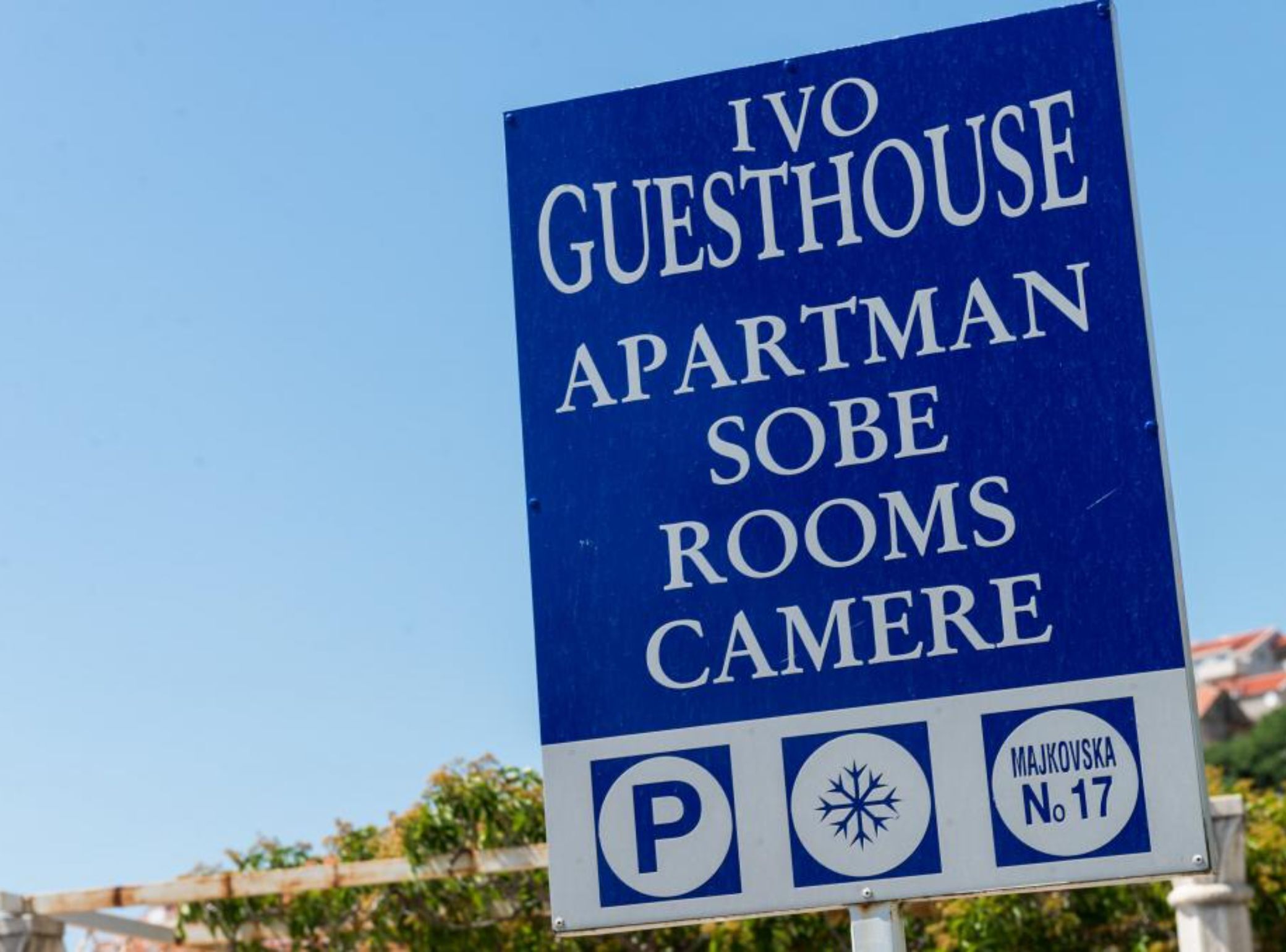 Une enseigne indique l’emplacement de l’auberge Ivo, en précisant qu’elle propose des chambres de type appartement et une salle dédiée à la photographie.