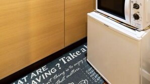 A modern kitchen with wooden cabinets, a microwave, and a kettle. - Tokinosyukudaikokucyou 1F (Osaka)
