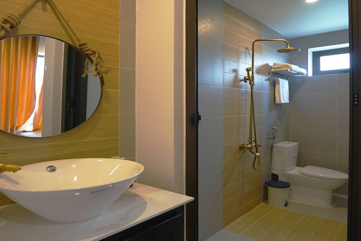 Un baño con un lavamanos grande de color blanco, un espejo y una zona de ducha.