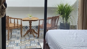 Un balcón con una cama, una mesa, dos sillas y una planta en maceta.