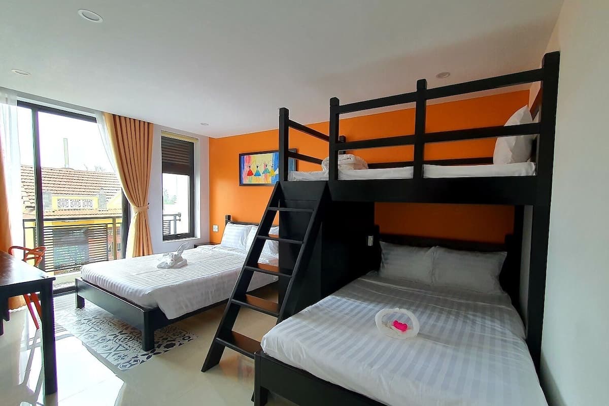 Habitación de hotel con dos literas, un escritorio y una ventana con cortinas.