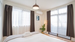 Een hotelkamer met een groot bed, een nachtkastje met een lamp en een potplant.