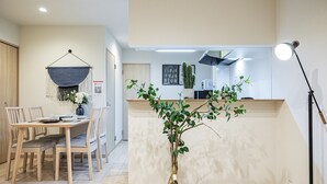 Een moderne keuken met een eethoek, een macramé wanddecoratie en een potplant.
