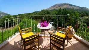 A balcony with two yellow chairs and a table, surrounded by a metal railing, overlooking a mountainous landscape. - Villa Ianthi, Stamoulis villas at the heart of the island (Kefalonia)