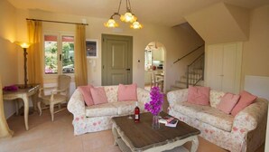 A cozy living room with two floral sofas, a wooden coffee table, and a dining area with a table and chairs. - Villa Ianthi, Stamoulis villas at the heart of the island (Kefalonia)
