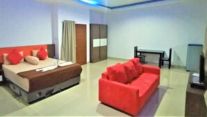 Una habitación de hotel con una cama, un sofá rojo, un escritorio y un armario.