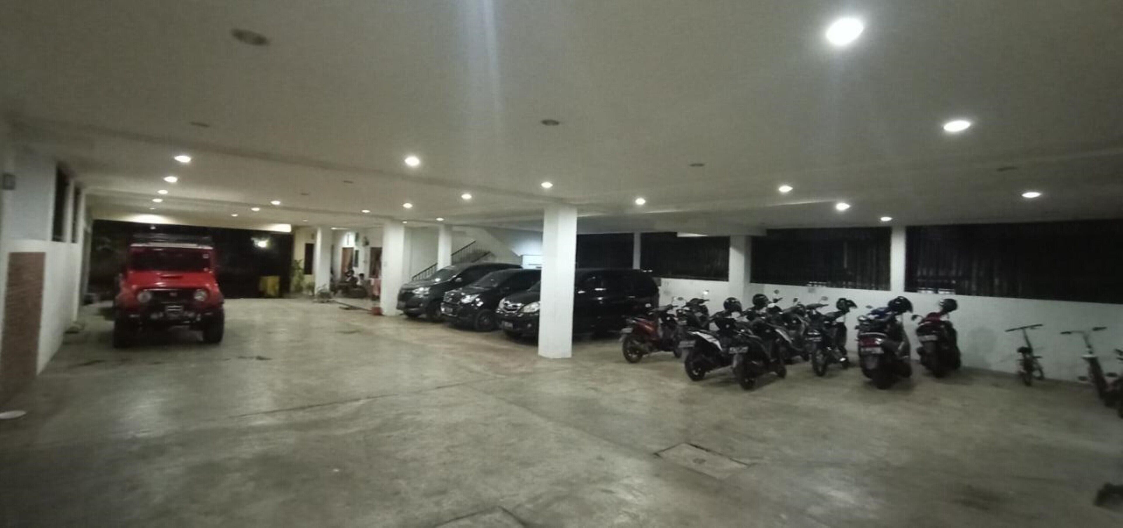 Un garaje de estacionamiento con varios autos y motocicletas aparcadas.