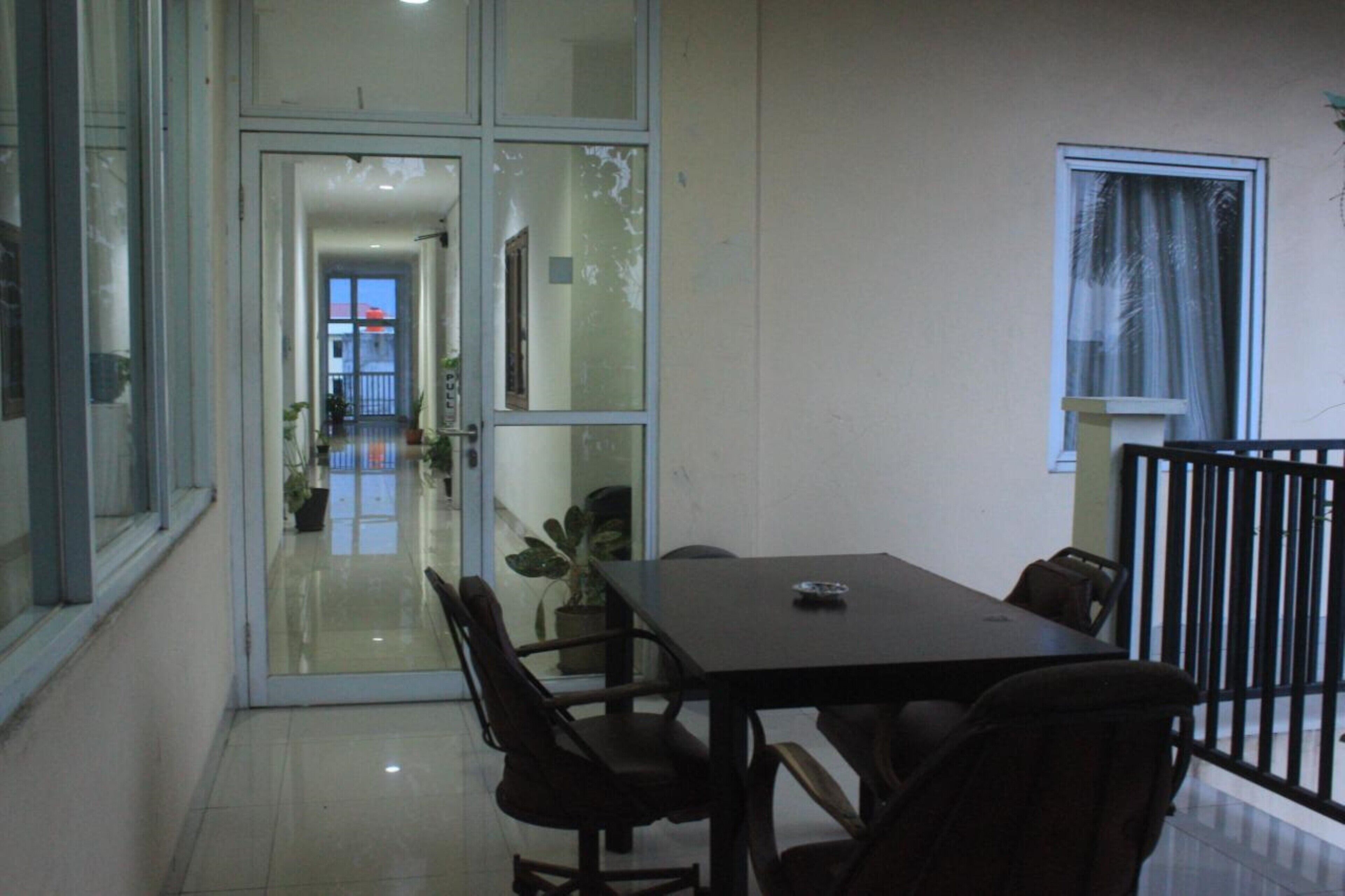 A dining area with a table and chairs, a glass door leading to a balcony, and a window with curtains.