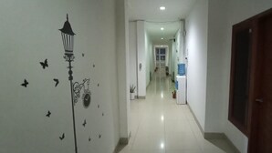 Un pasillo con un reloj y adhesivos de mariposas en la pared, un dispensador de agua y una puerta a la derecha.