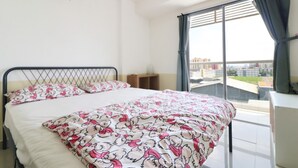 Ein Schlafzimmer mit Bett, einem Fenster mit Vorhängen und einer Klimaanlage an der Wand.
