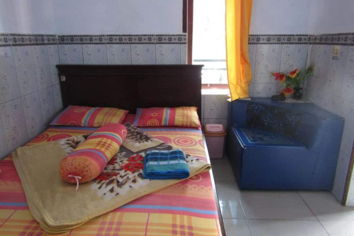 A bed with colorful bedding and a blue bathtub in a room with patterned walls and a window with yellow curtains.