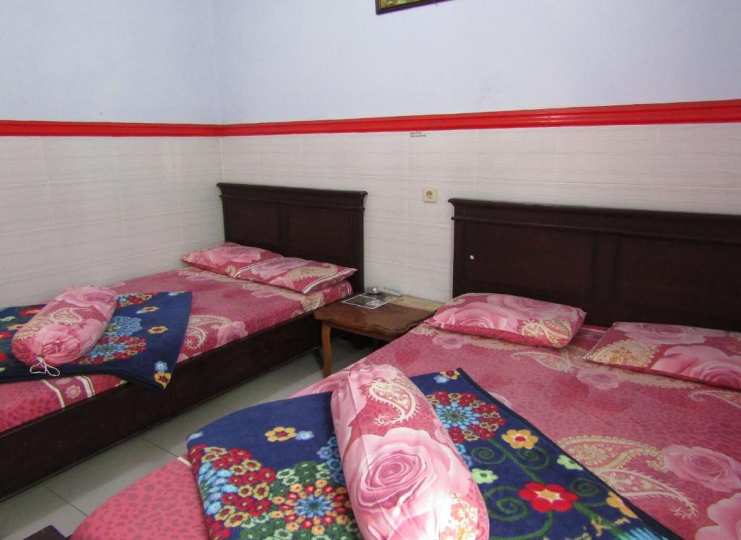 Quarto com duas camas de solteiro, cada uma com roupa de cama estampada e cabeceiras de madeira.