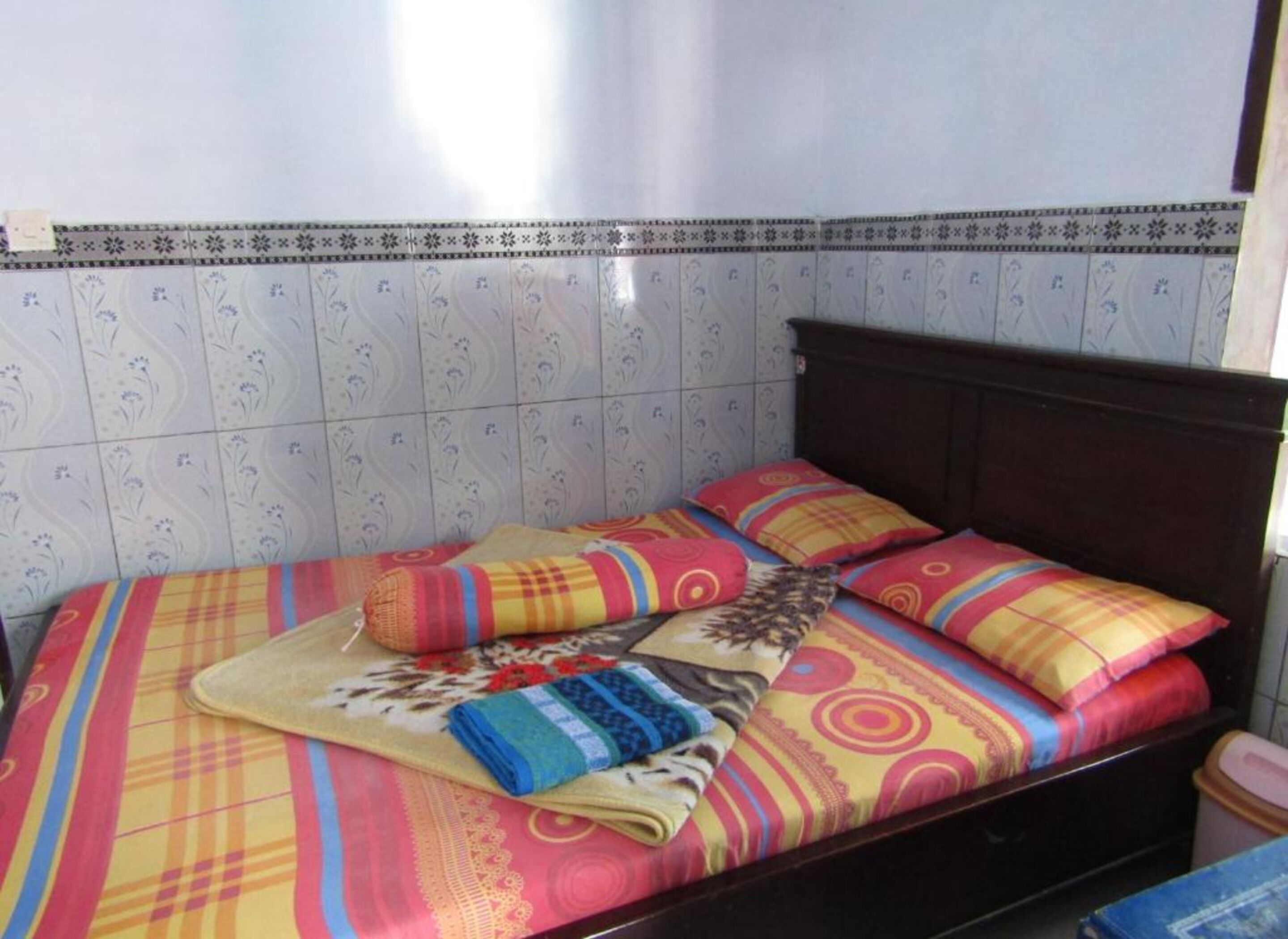 Een bed met kleurrijk beddengoed en een gestreept hoofdeinde.
