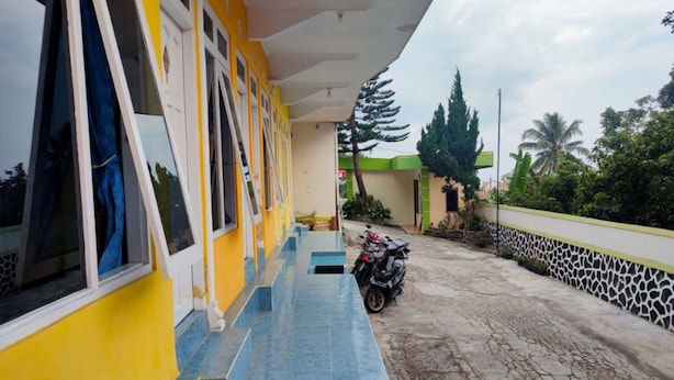 A building with a yellow exterior, blue tiled steps, and a parked motorcycle. - Hotel Abimanyu Bandungan (Bandungan)