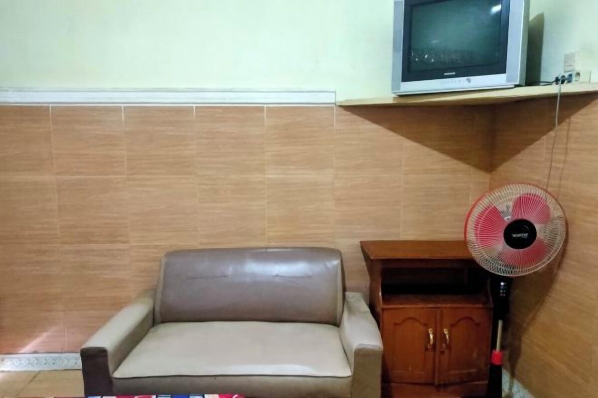 A room with a sofa, a wooden cabinet, and a wall-mounted TV.