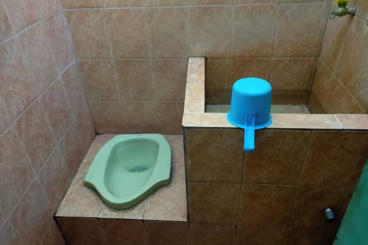 Une petite salle de bain carrelée, avec des toilettes à la turque vertes et un bidet bleu.