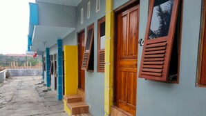 A row of colorful buildings with wooden doors and windows, a concrete floor, and a visible staircase. - Hotel Abimanyu Bandungan (Bandungan)