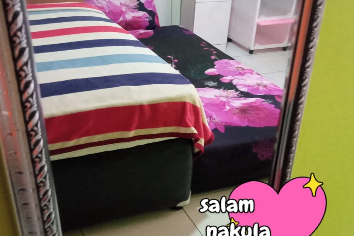 A room with a bed, a mirror, and a white cabinet.