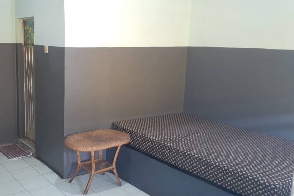 A small room with a bed, a chair, a radiator, and a door.