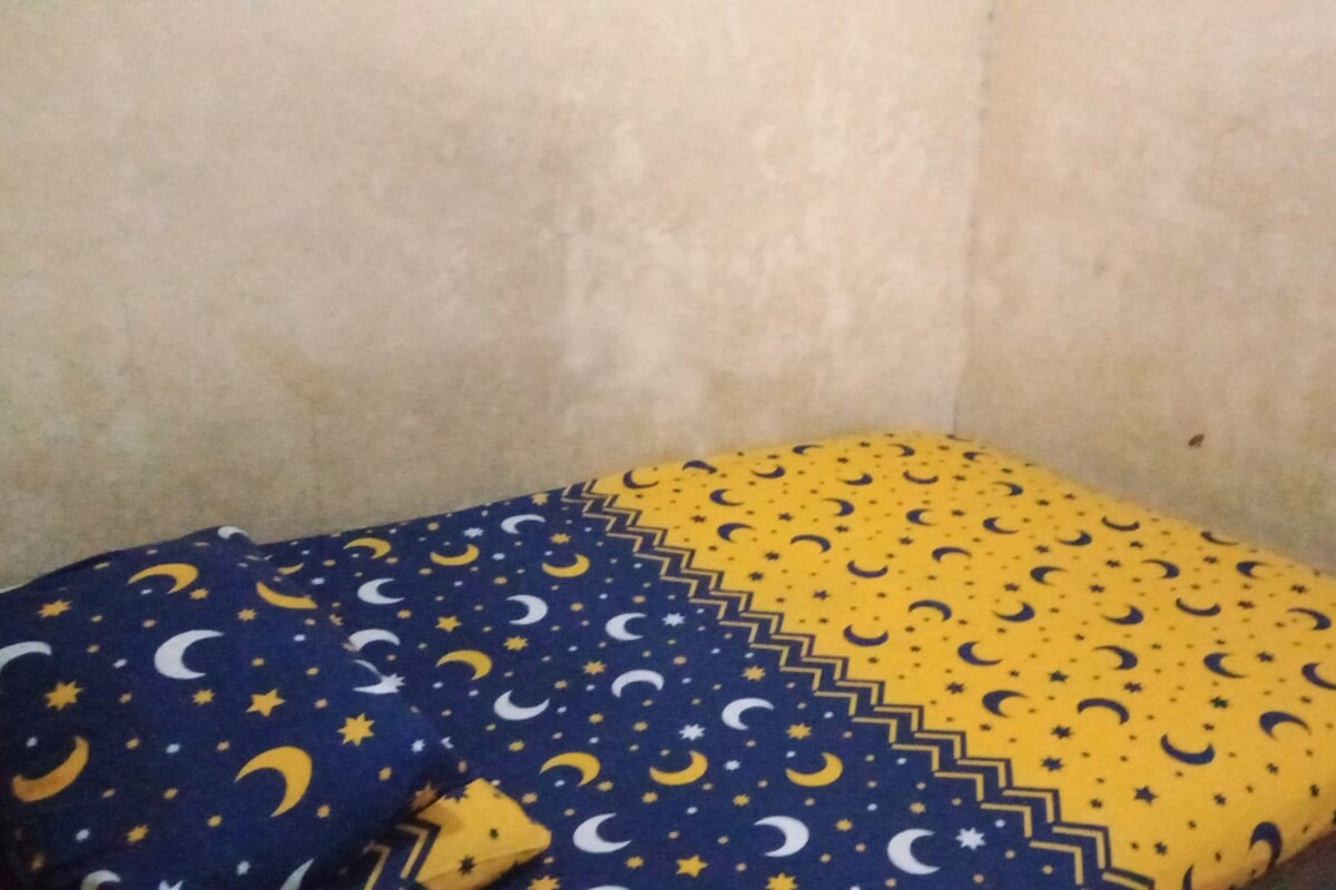 A bed with a patterned bedspread featuring crescent moons and stars.