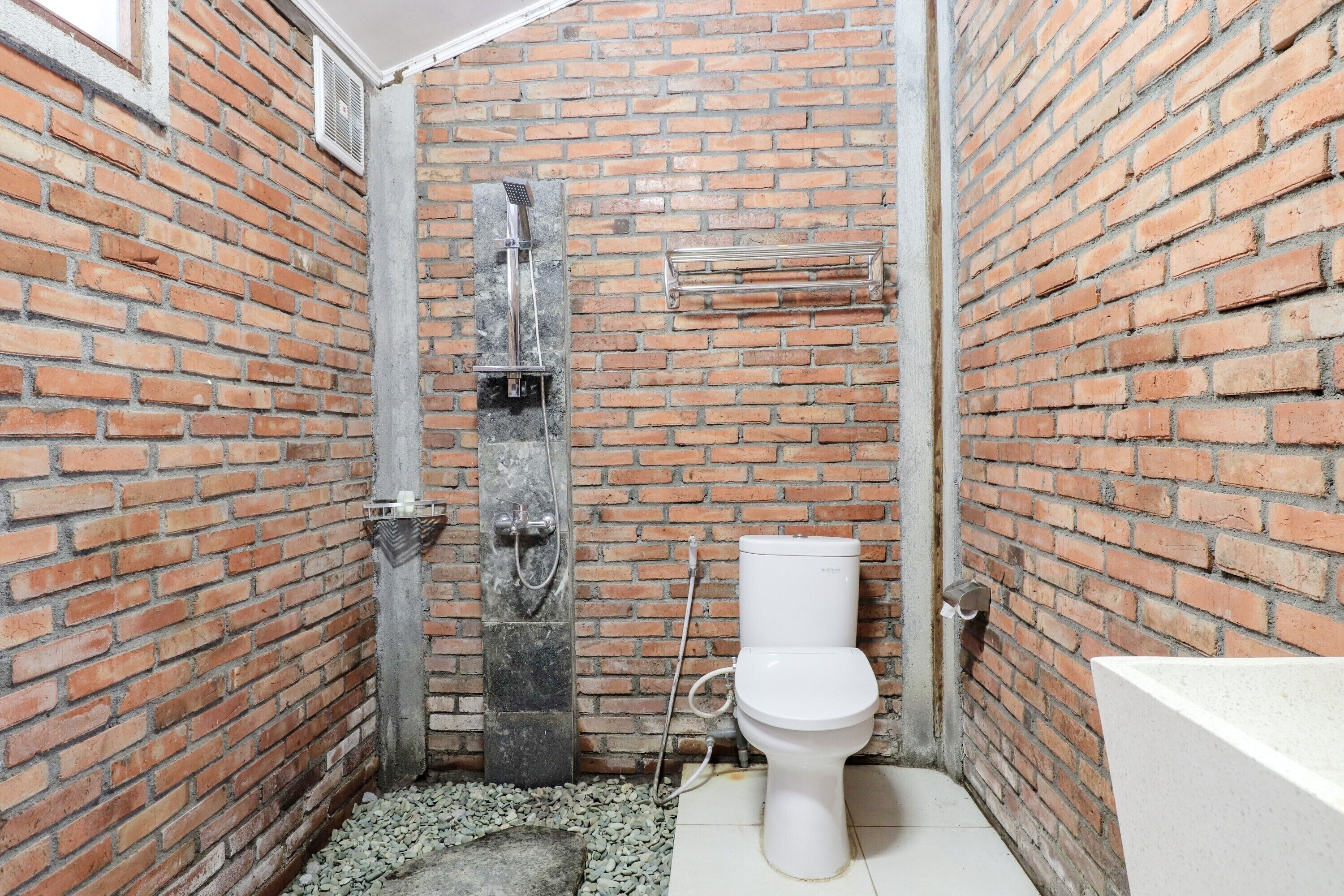 Une salle de bain avec un mur en briques, une douche, des toilettes et une baignoire.