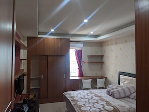 A bedroom with a bed, a desk, and a wardrobe. - Pinewood Apartment by Vial (Cileunyi)