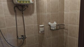 Un baño pequeño con inodoro, ducha y dispensador de jabón.