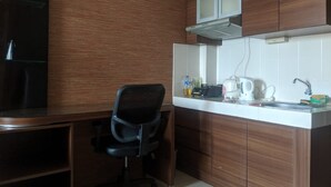 Cocina compacta con armarios de madera, estufa a gas empotrada, hervidor y pileta.