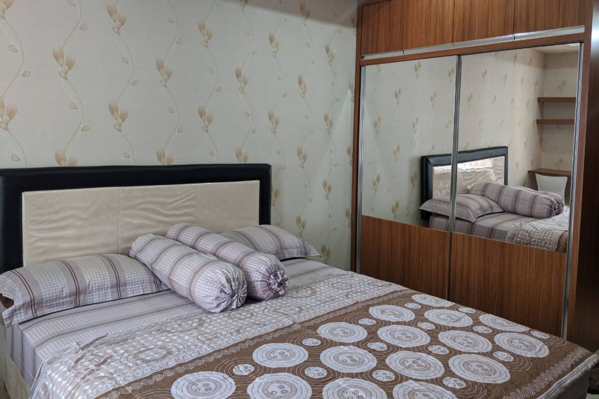A bedroom with a bed, a mirror, and a wardrobe.