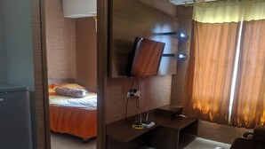 Habitación de hotel con cama, televisor montado en la pared, escritorio y una silla.