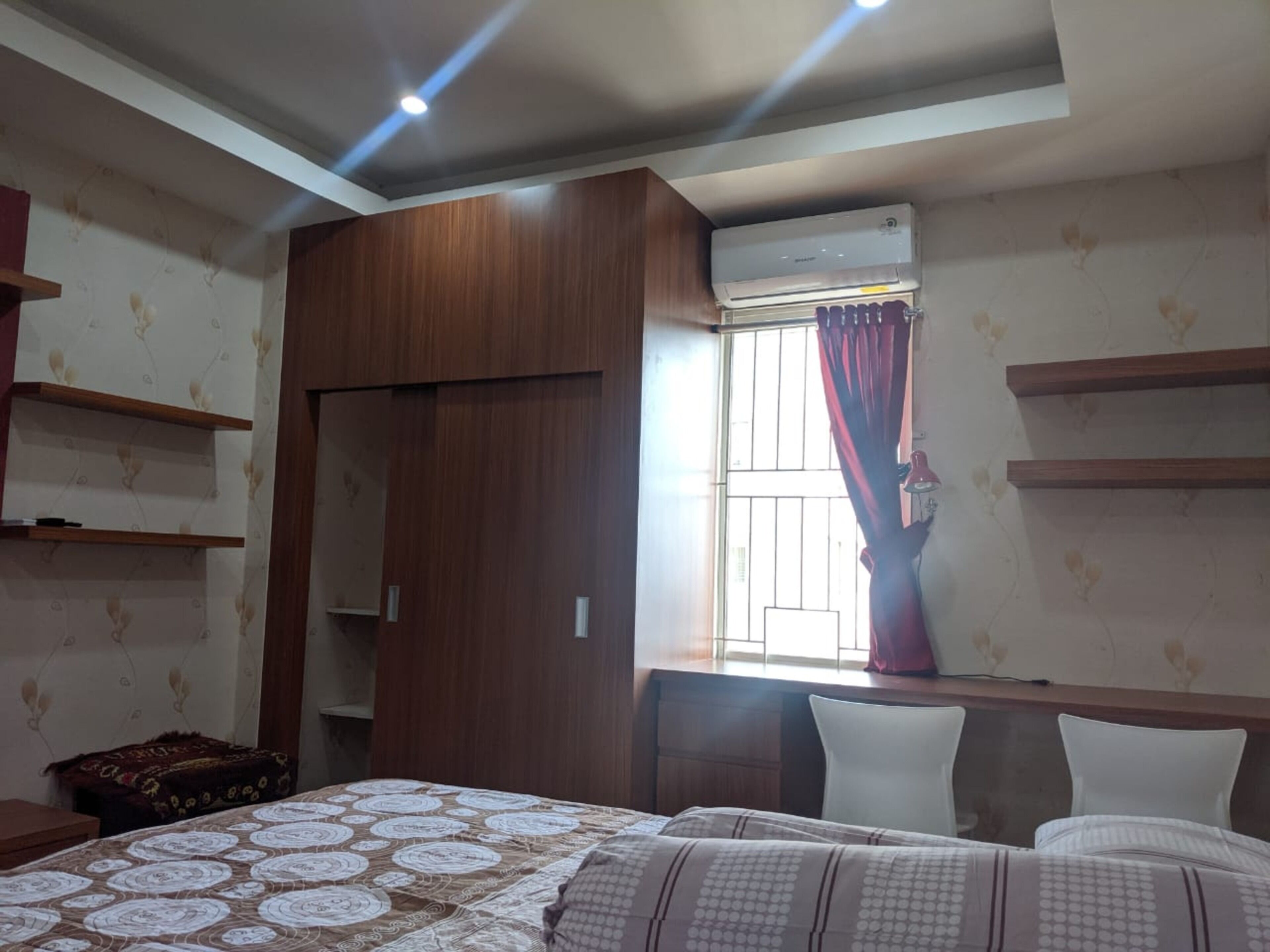 Une chambre à coucher comprenant un lit, une armoire, un bureau et une fenêtre avec des rideaux.