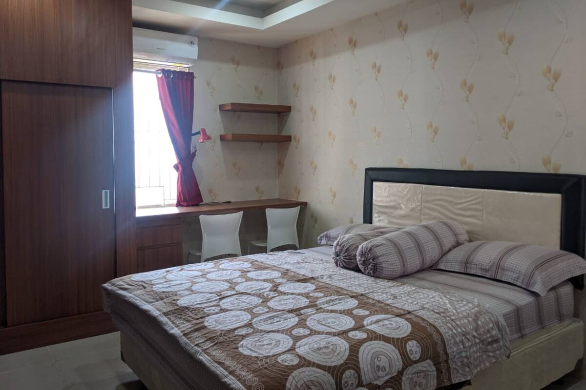 A bedroom with a bed, a desk, and a wardrobe.