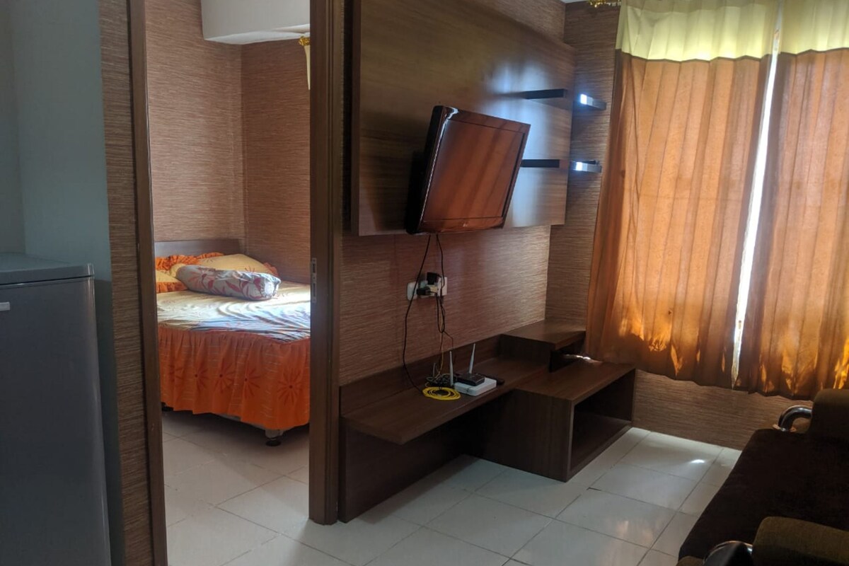 Une chambre d’hôtel avec un lit, un téléviseur fixé au mur, un bureau et une chaise.