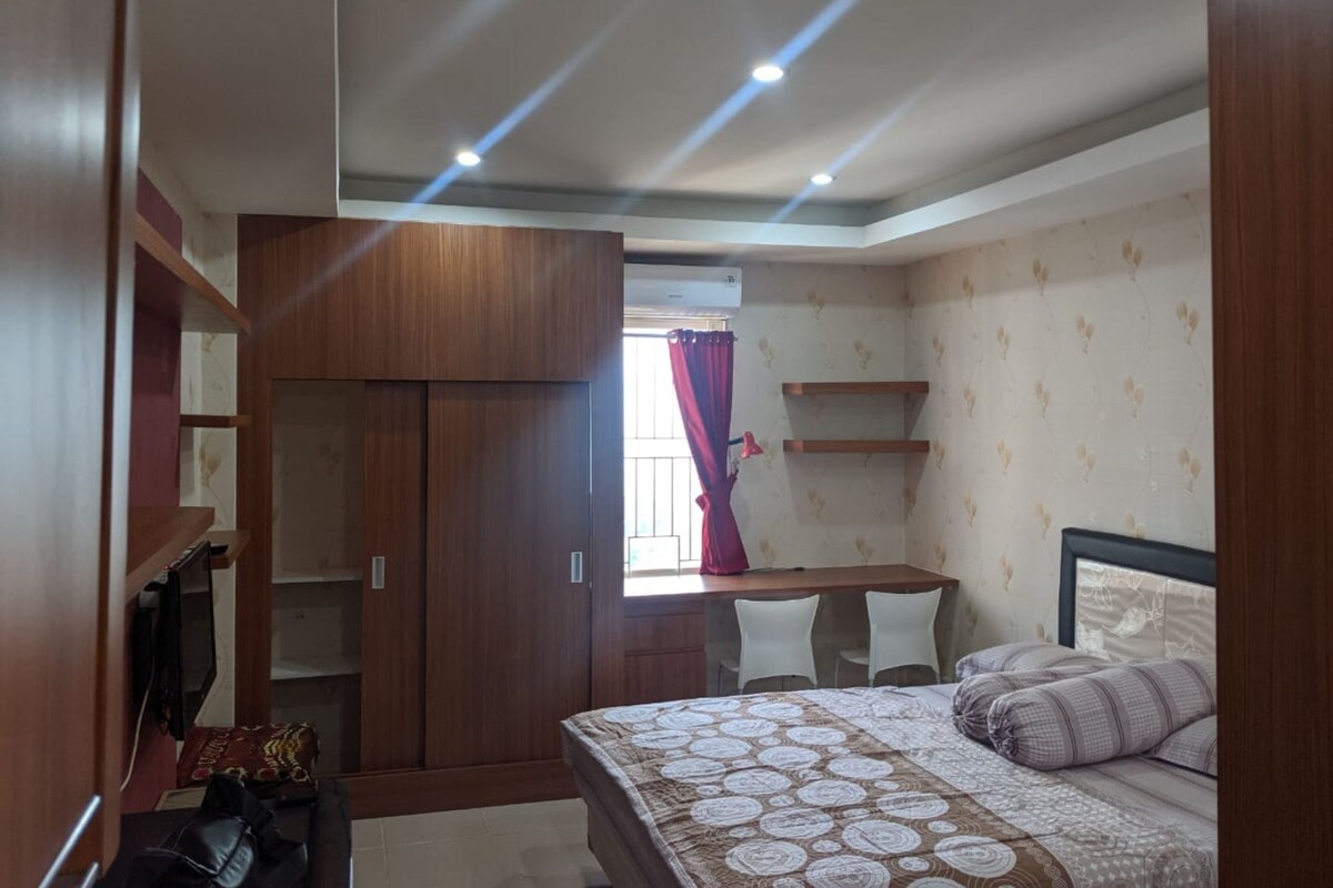 A bedroom with a bed, a desk, and a wardrobe.