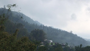 A view of a mountainous landscape with a red wall in the foreground and a blanket hanging on it. - Villa Bintang (Malang)