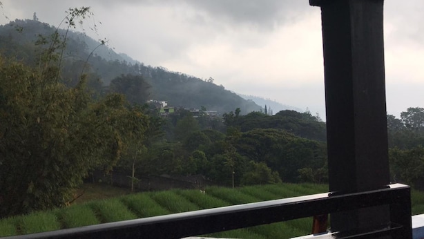 A view of a rural landscape with a hill, trees, and a building in the distance. - Villa Bintang (Malang)
