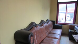 A row of leather sofas with a high backrest and armrests, a tiled floor, and a window with a view of parked cars outside. - Hotel Kopeng Indah 1 (Getasan)