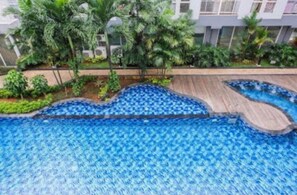 Una piscina con muelle de madera y follaje circundante.
