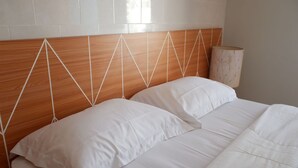 Ein Bett mit weißer Bettwäsche und einem Holz-Kopfstück mit geometrischen Mustern.