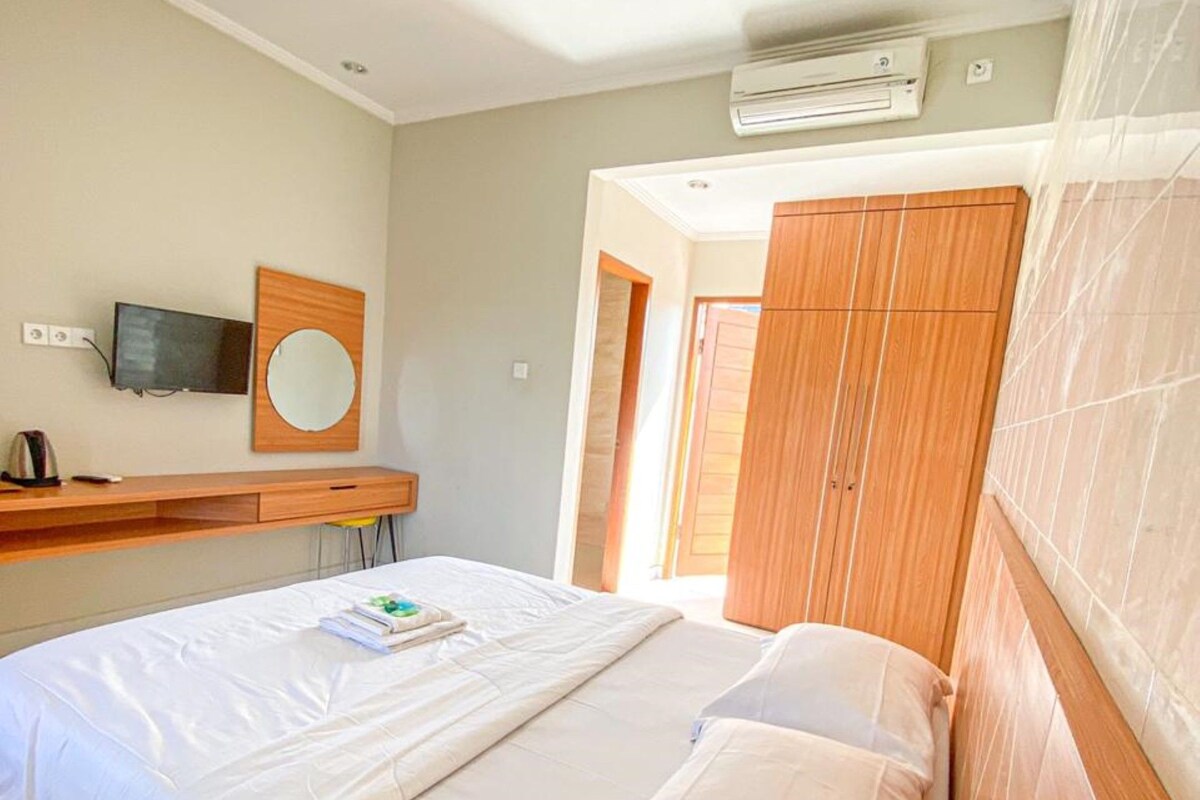 Une chambre à coucher comprenant un lit, un bureau avec une télévision, un miroir et un appareil de climatisation.