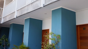 Ein Gebäude mit blauer Fassade, weißen Balkonen und einem gefliesten Eingangsbereich.