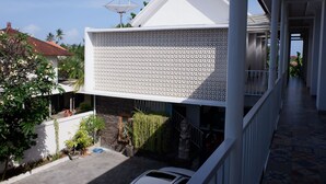 Ein modernes Gebäude mit weißer Fassade, einem Balkon mit ornamentiertem Geländer und einer Sat-Anlage auf dem Dach.