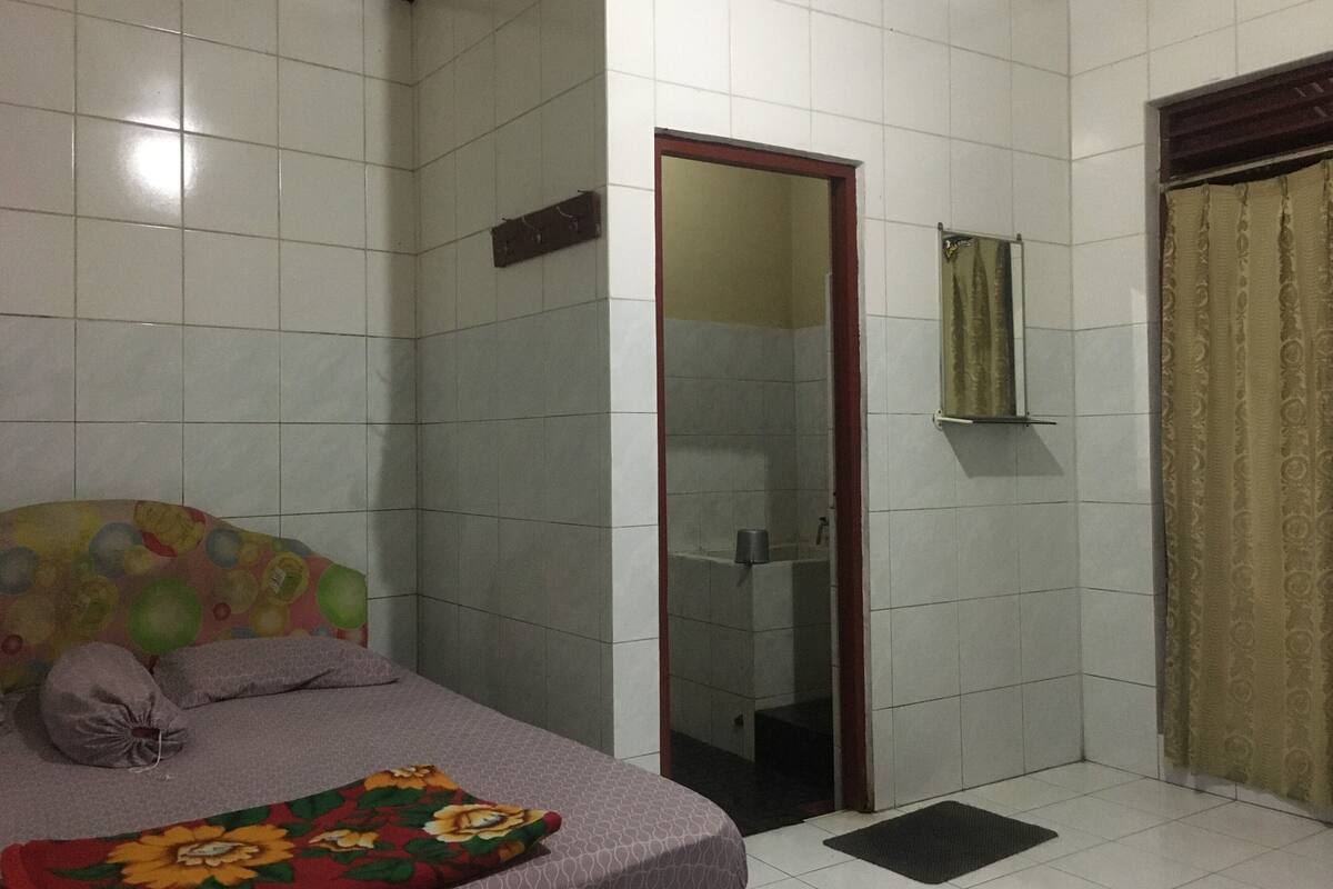 Een slaapkamer met een bed, een badkamer met een spiegel en een douche.
