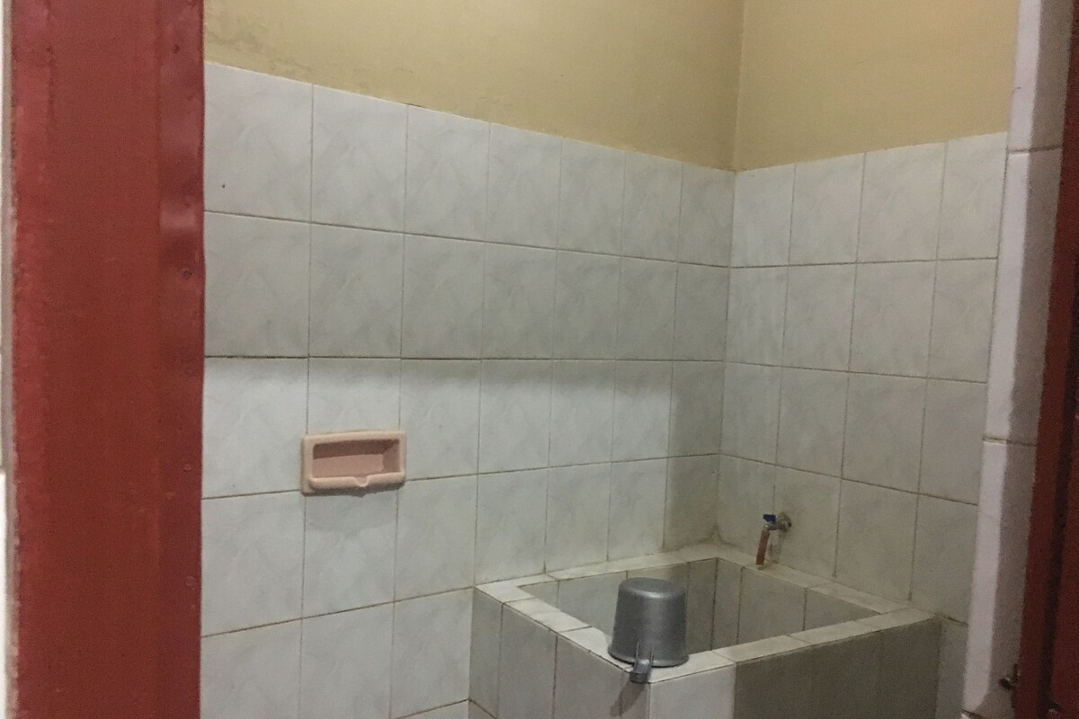 Een kleine betegelde badkamer met een douchegedeelte, een zeepbakje en een handdroger.