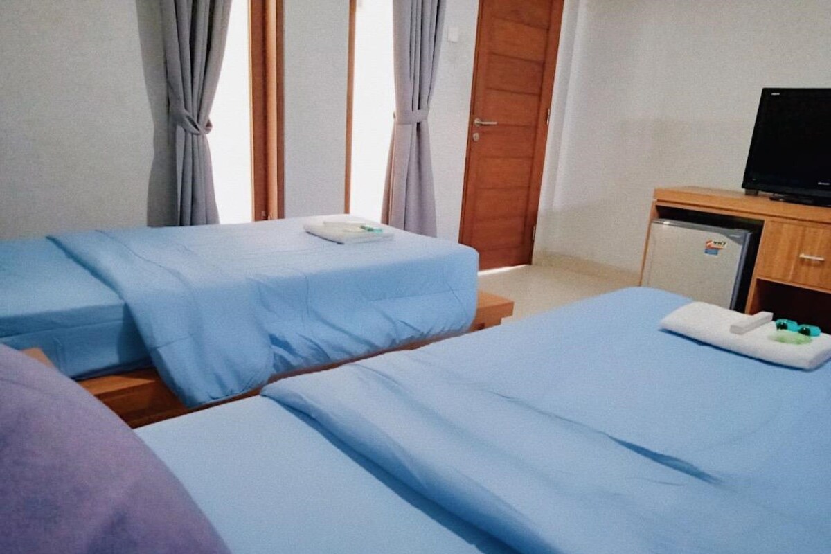 A hotel room with two beds, a television, and a small refrigerator.