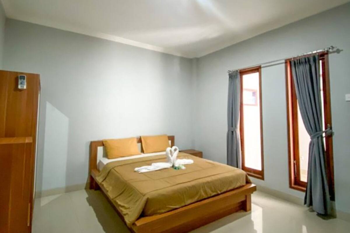 A bedroom with a bed, a wardrobe, and a window with curtains.